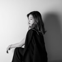 a black and white photo of a woman leaning against a wall